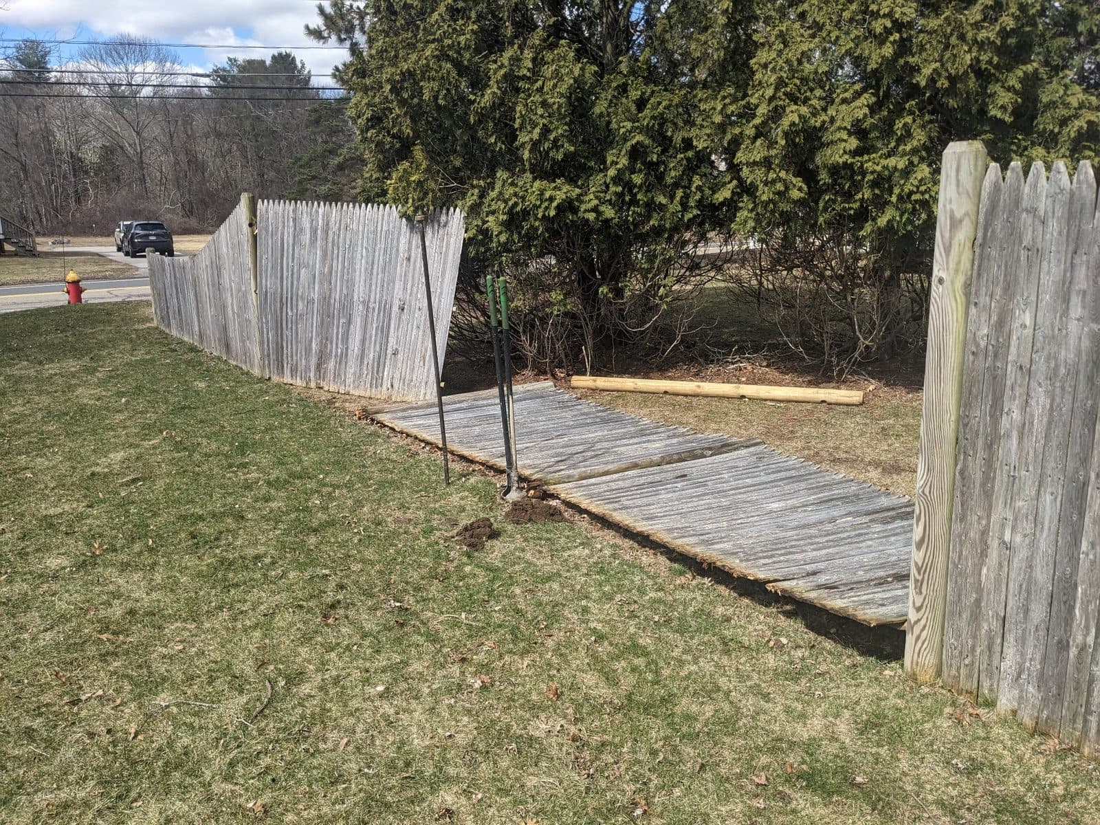 Collapsed wood fence with broken posts before repair
